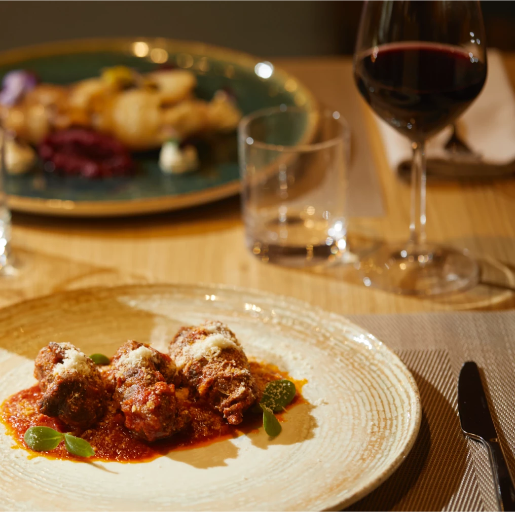 Polpette al sugo servite con vino rosso in un elegante ristorante